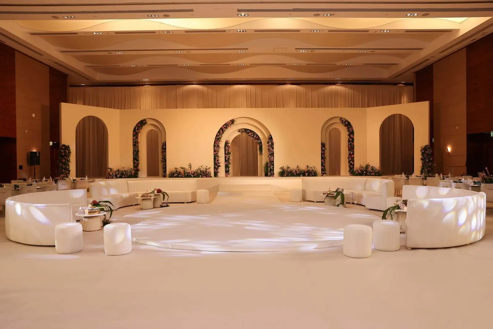 Ivory arches and curved lounges in a wedding hall